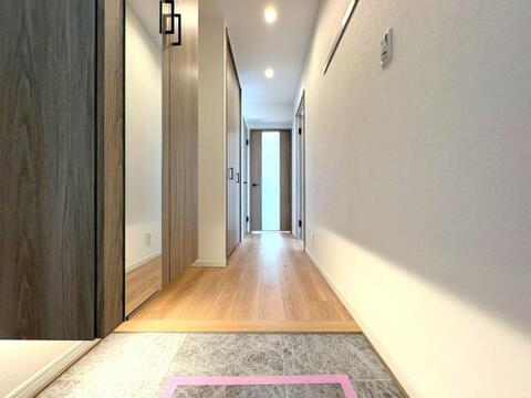 上質な木目ドアとシックな床タイルがマッチした玄関廊下。姿見付きのシューズボックスを備えており、お出かけ前の身だしなみチェックにも便利です。