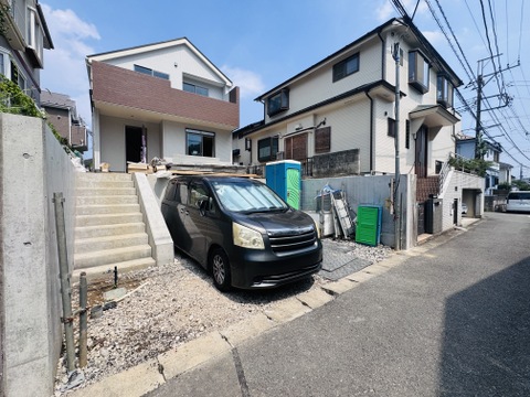 住宅の外観と敷地内の駐車スペースが見える風景
