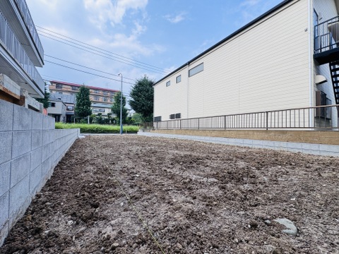 建物に囲まれた更地の売土地の様子