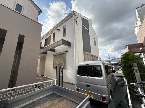 三階建ての住宅と敷地内の駐車スペースの外観です