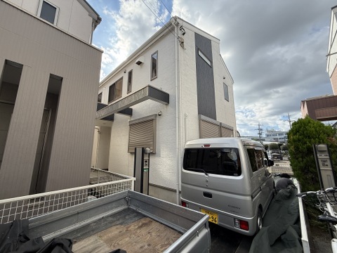 都市部の住宅街にある2階建ての住宅と駐車スペース