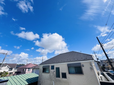 住宅街の中にある二階建ての家と晴天の空の風景