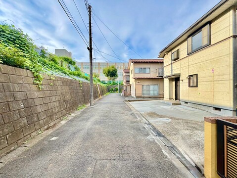 住宅前の道路と駐車スペース、塀に囲まれた周辺環境