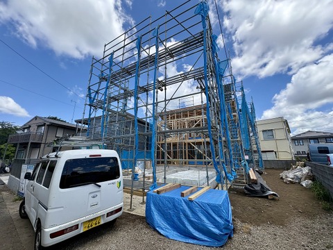 外観工事中の住宅と駐車スペースが見える現場写真です