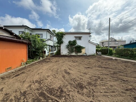 敷地の整地された宅地の様子、周囲に住宅が見える