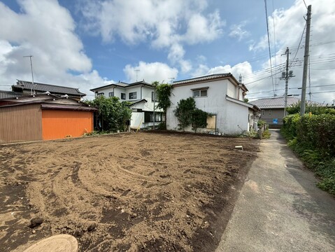 住宅地内の更地、周囲に住宅が建ち並ぶ