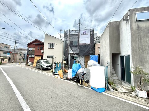 道路沿いに建つ住宅と作業中の人々の様子