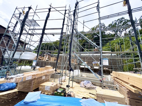 工事中の木造住宅の骨組みと周辺の緑豊かな環境