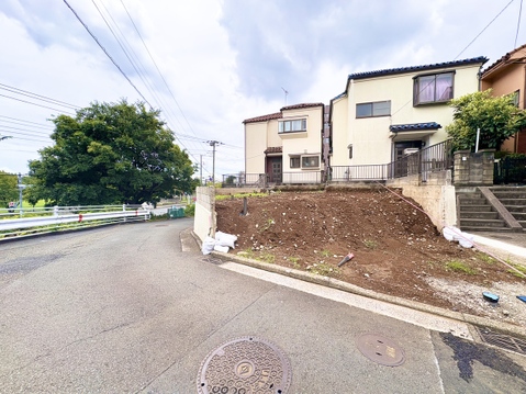 道路沿いの住宅用土地、周辺に住宅が立ち並ぶ