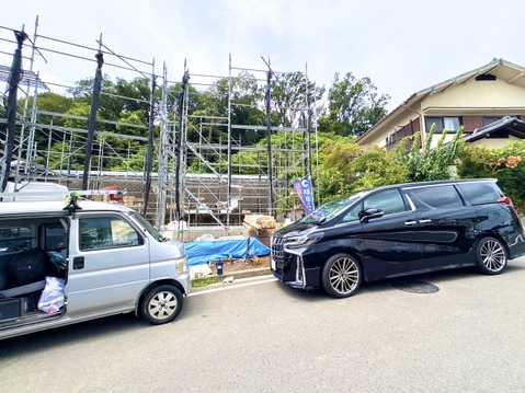建築現場の前に並ぶ車と住宅の外観です