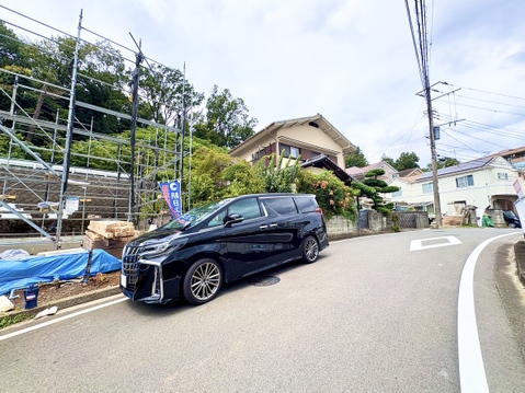坂道沿いに建つ住宅と駐車中の車の様子