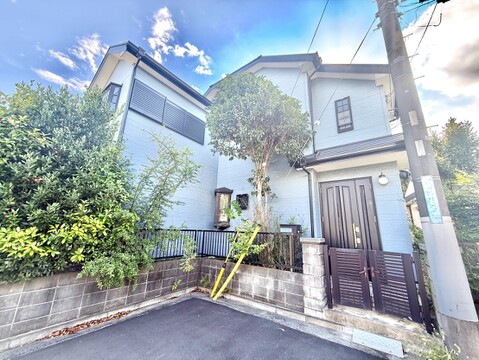 緑に囲まれた二階建て住宅の外観です