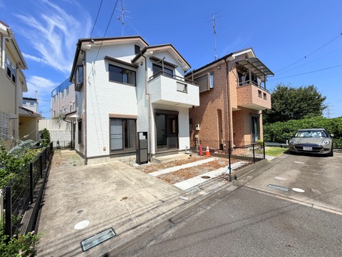 角地に建つ2階建ての住宅と駐車スペース