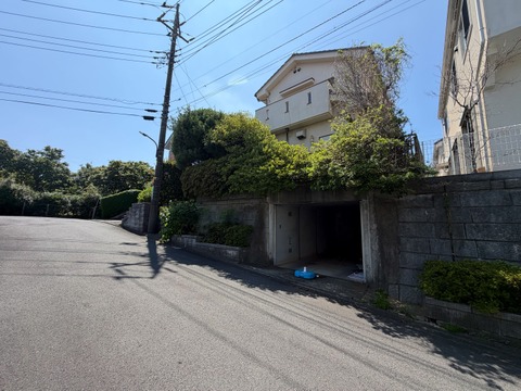 道路に面した高台の住宅外観と周辺の街並み