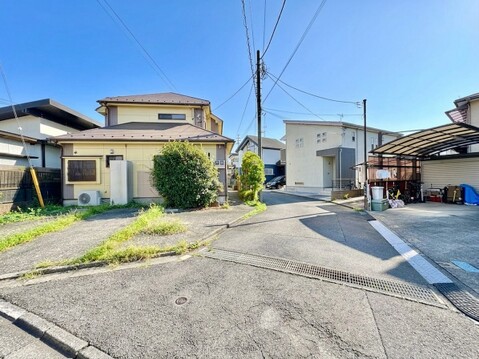 二階建て住宅の外観と周辺の街並みが見える風景です