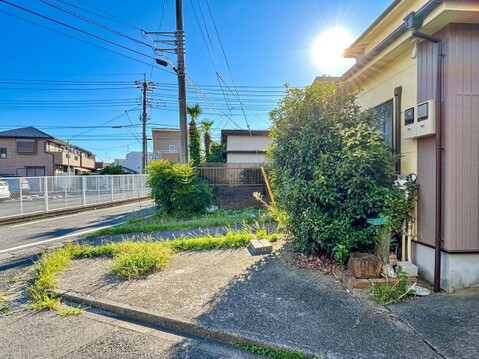 住宅の外観と庭、隣接道路が見える風景