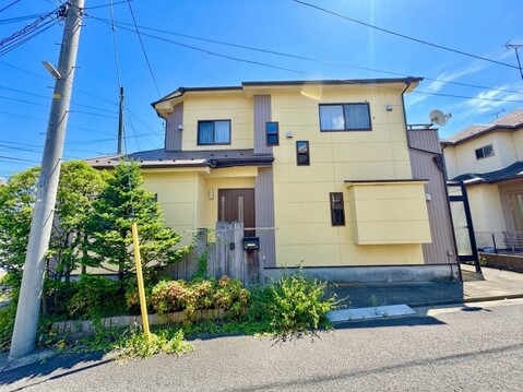2階建ての住宅、周囲に電柱や植栽がある外観です