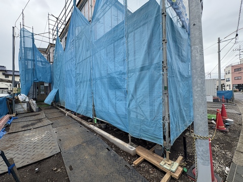 青い防護ネットで囲まれた建築中の建物