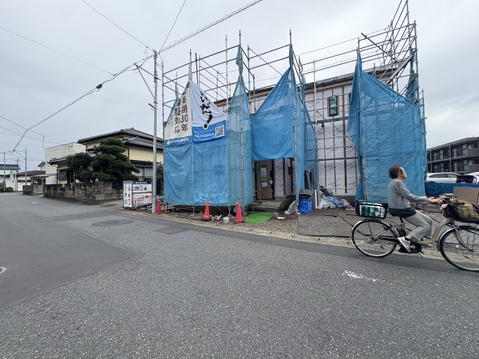 道路沿いの建築中物件青い養生シートで覆われている