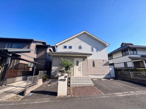 白い外壁の戸建住宅が並ぶ静かな住宅街の外観です