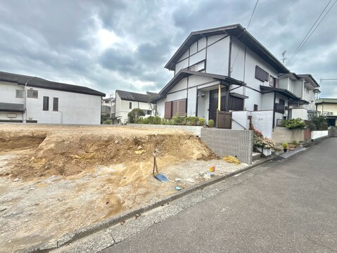 住宅街の一角にある空地と隣接する住宅の外観