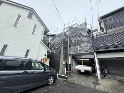 外装工事中の住宅が並ぶ狭い道路沿いの物件です