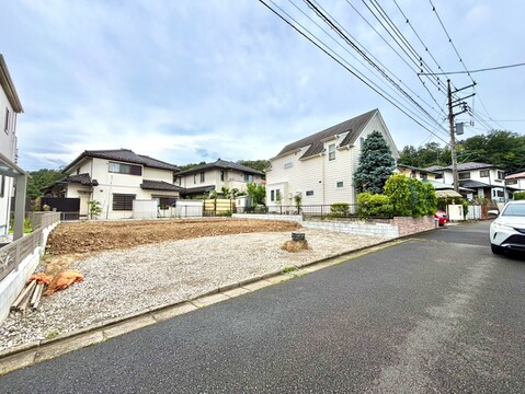 住宅街にある更地の土地、周囲に家並みが見える