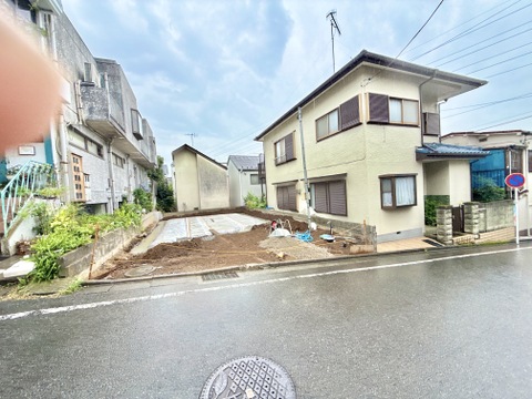 道路に面した更地の住宅用地、周囲に住宅が並ぶ環境