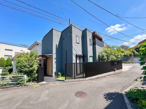 緑に囲まれた角地の現代的な二階建て住宅です
