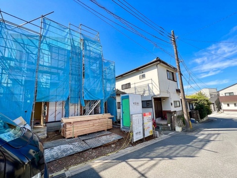 道路沿いに建つ住宅と隣接する建築中の建物