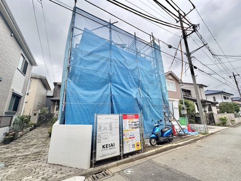 青いシートで覆われた建築中の建物と前面道路