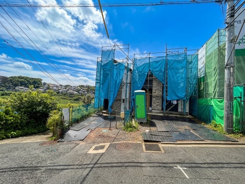 青空の下にある建築中の建物と前面道路