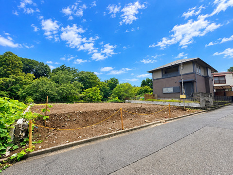 緑に囲まれた戸建て外観と前面道路