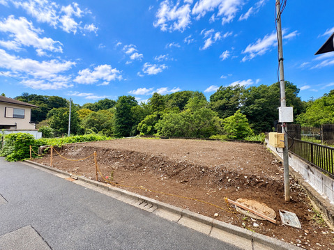道路沿いの更地と周辺の住宅街