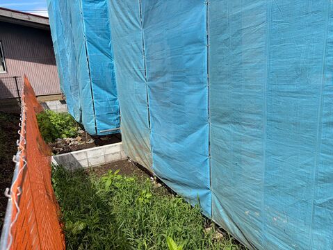 青い養生シートで覆われた建物脇の通路