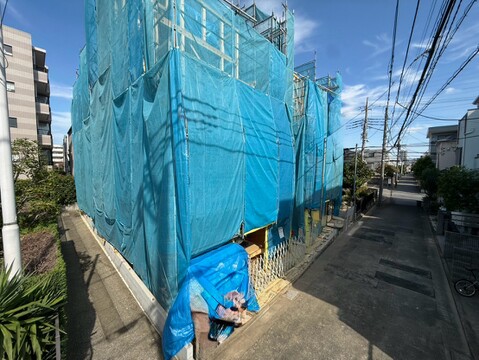 青いシートで覆われた建物と前面道路