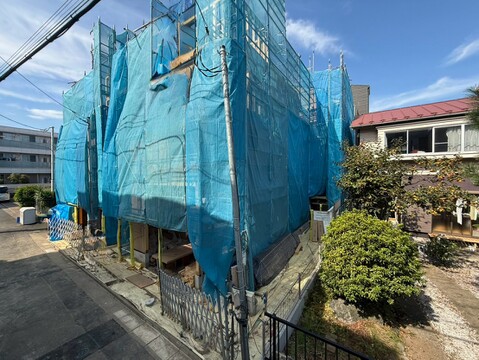 青い養生シートで覆われた建物と植栽