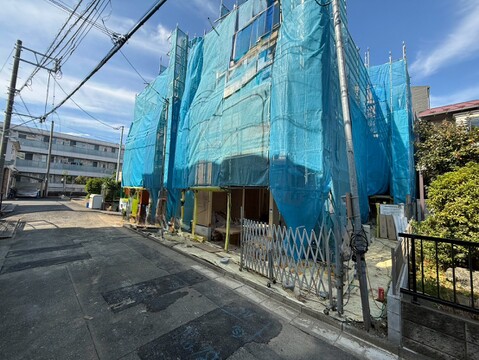 青いシートで覆われた建築中の建物と前面道路