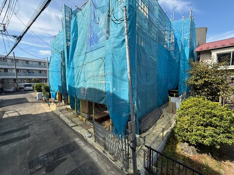 青いシートで覆われた建物と周辺の植栽