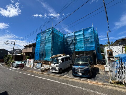 青いネットで覆われた建築中の建物と前面道路