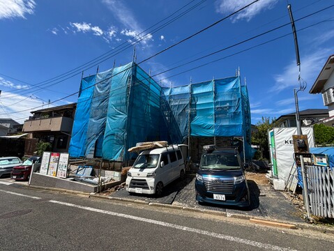 青い外壁の建物と前面道路、駐車場を望む外観