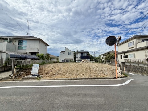 道路沿いの更地と周辺住宅