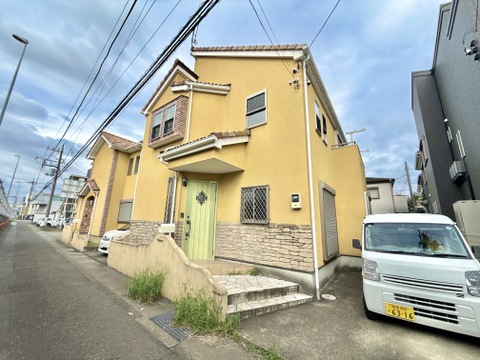 黄色い外壁の2階建て住宅と前面道路