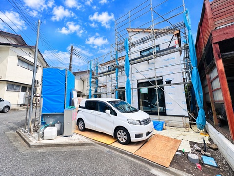 建築中の建物と前面道路、駐車中の車