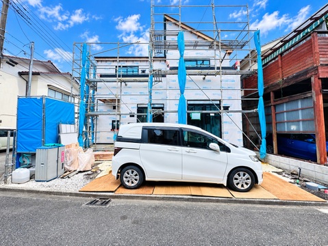 建物外観と前面道路、白い車を確認できる