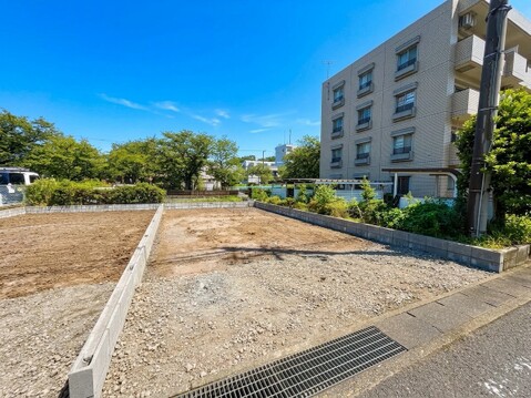 建築前の区画された更地周辺に住宅や建物が見える