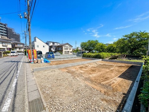 道路沿いの整形地周囲に住宅と緑が見える