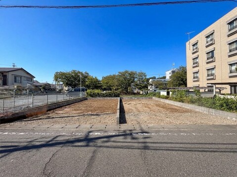 道路沿いの更地と周辺の建物
