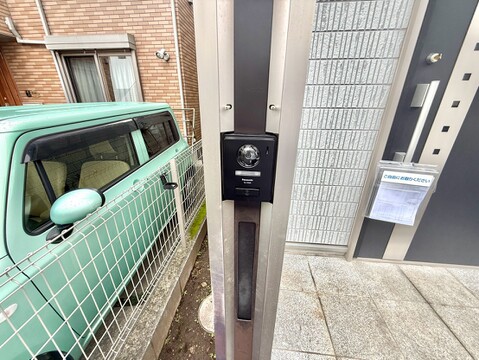 建物前の門柱とインターホン、隣接する車を撮影