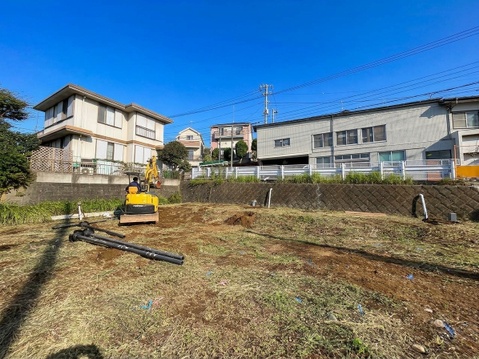 建物に囲まれた土の敷地と周辺の住宅